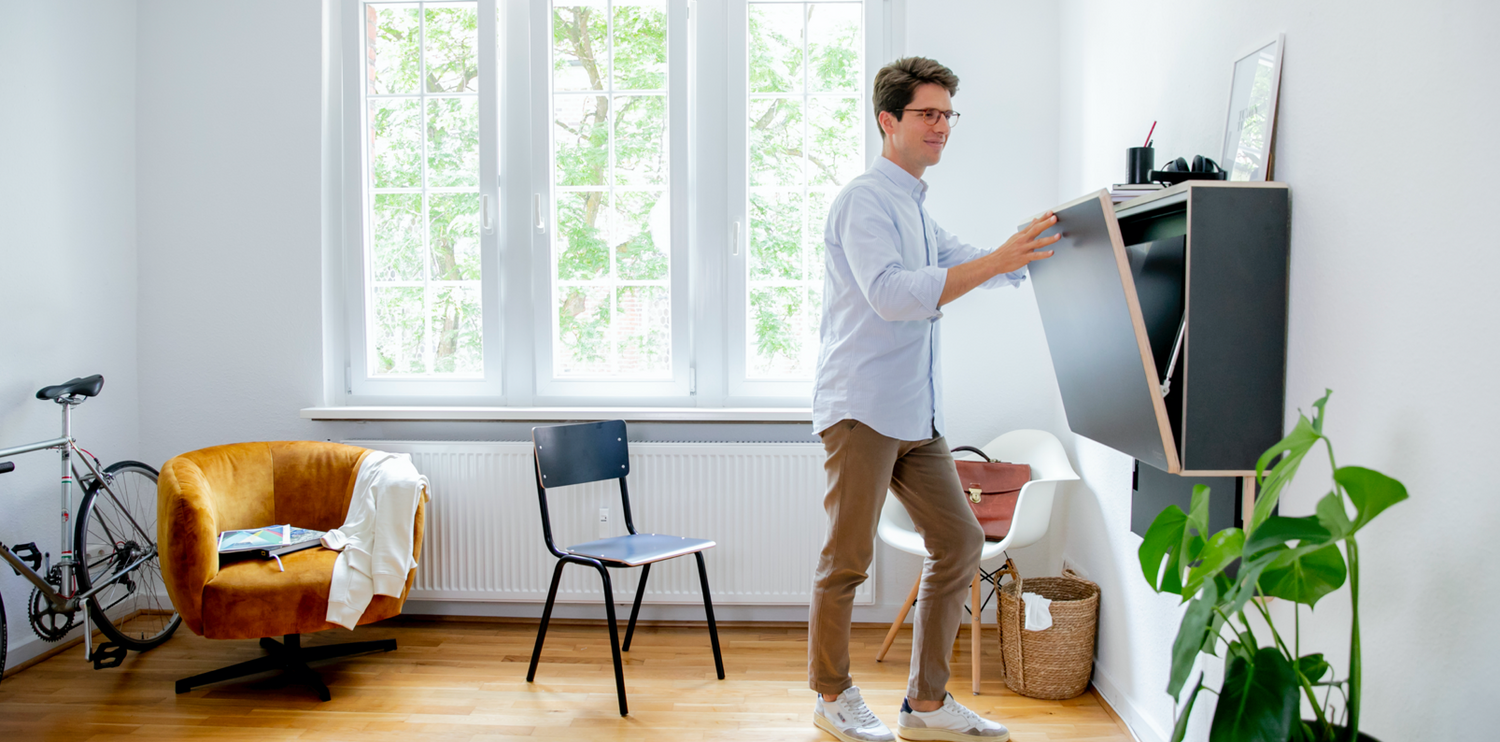 Ein Mann schließt gerade die Klappe seines anthrazitfarbenen Klappt. und lächelt dabei.